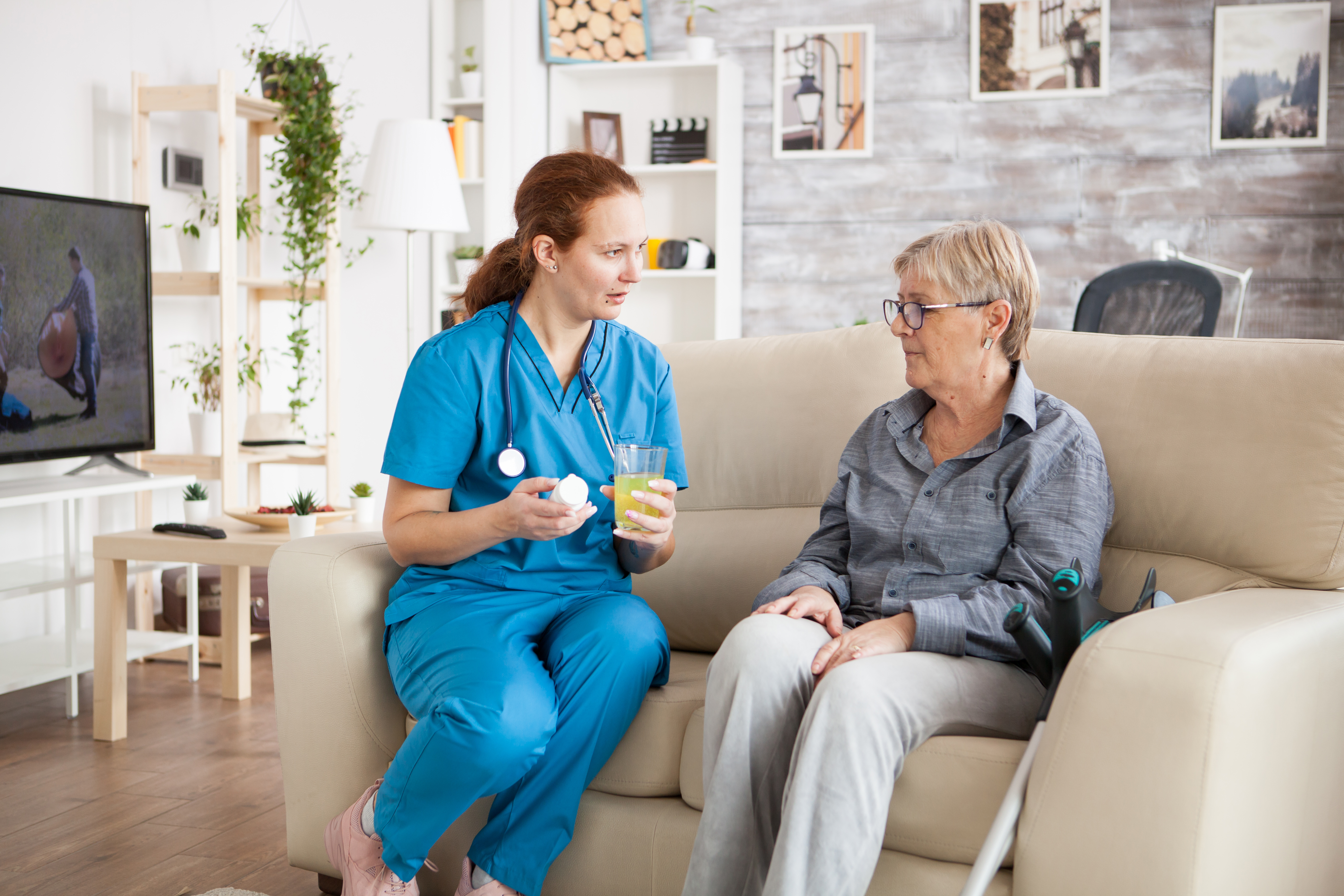 Registered nurse assisting a senior with scheduling on a tablet in a well-organized home
