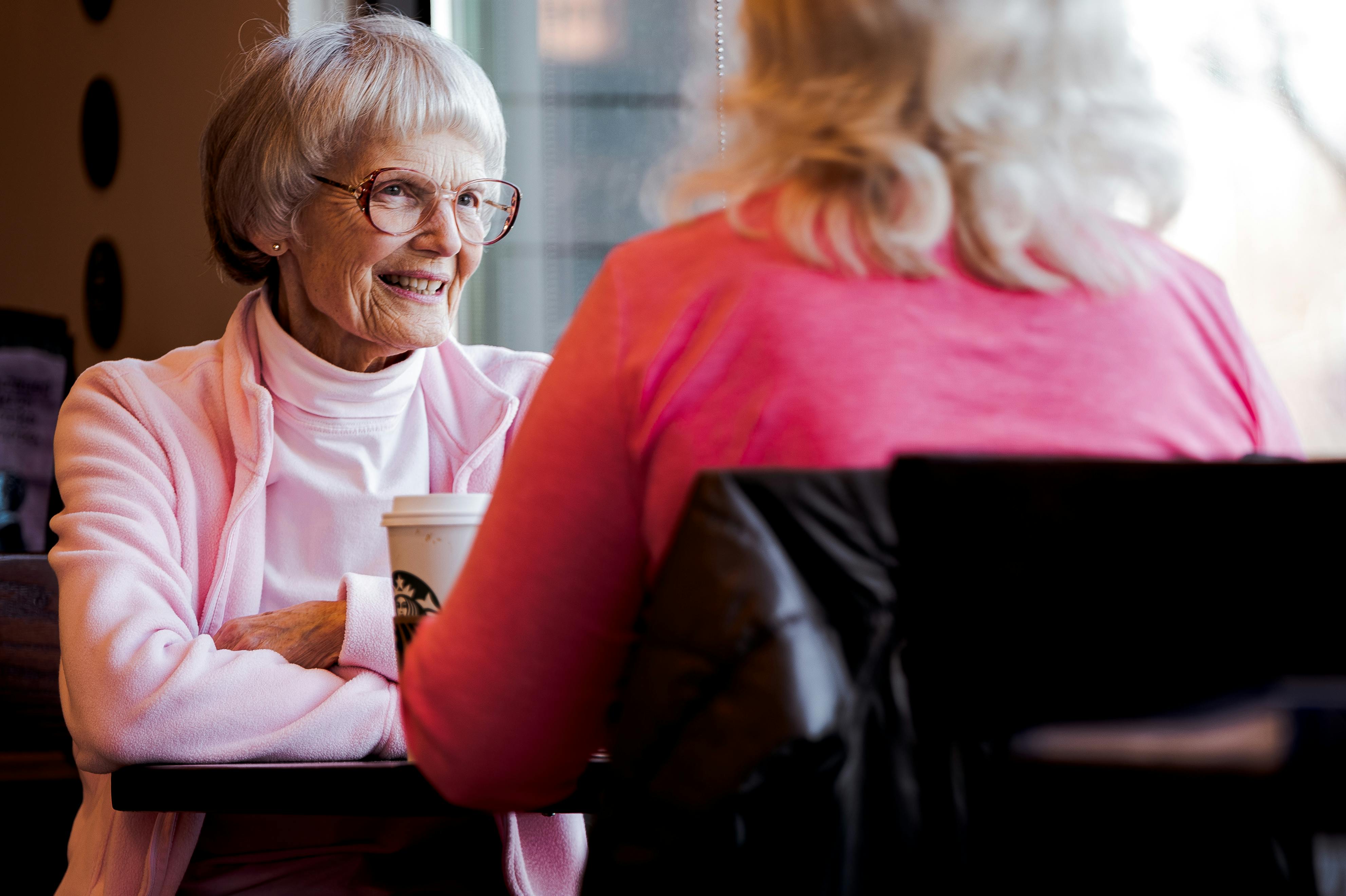 Friendly caregiver reading a book with an elderly patient in their living room